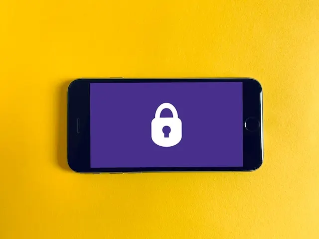 Smartphone on yellow background displaying a padlock symbol, indicating security.