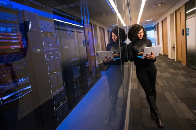 A woman in a black shirt working on a Surface laptop.